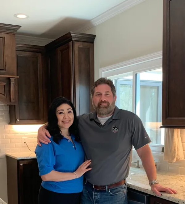 A man and woman standing in front of a kitchen.