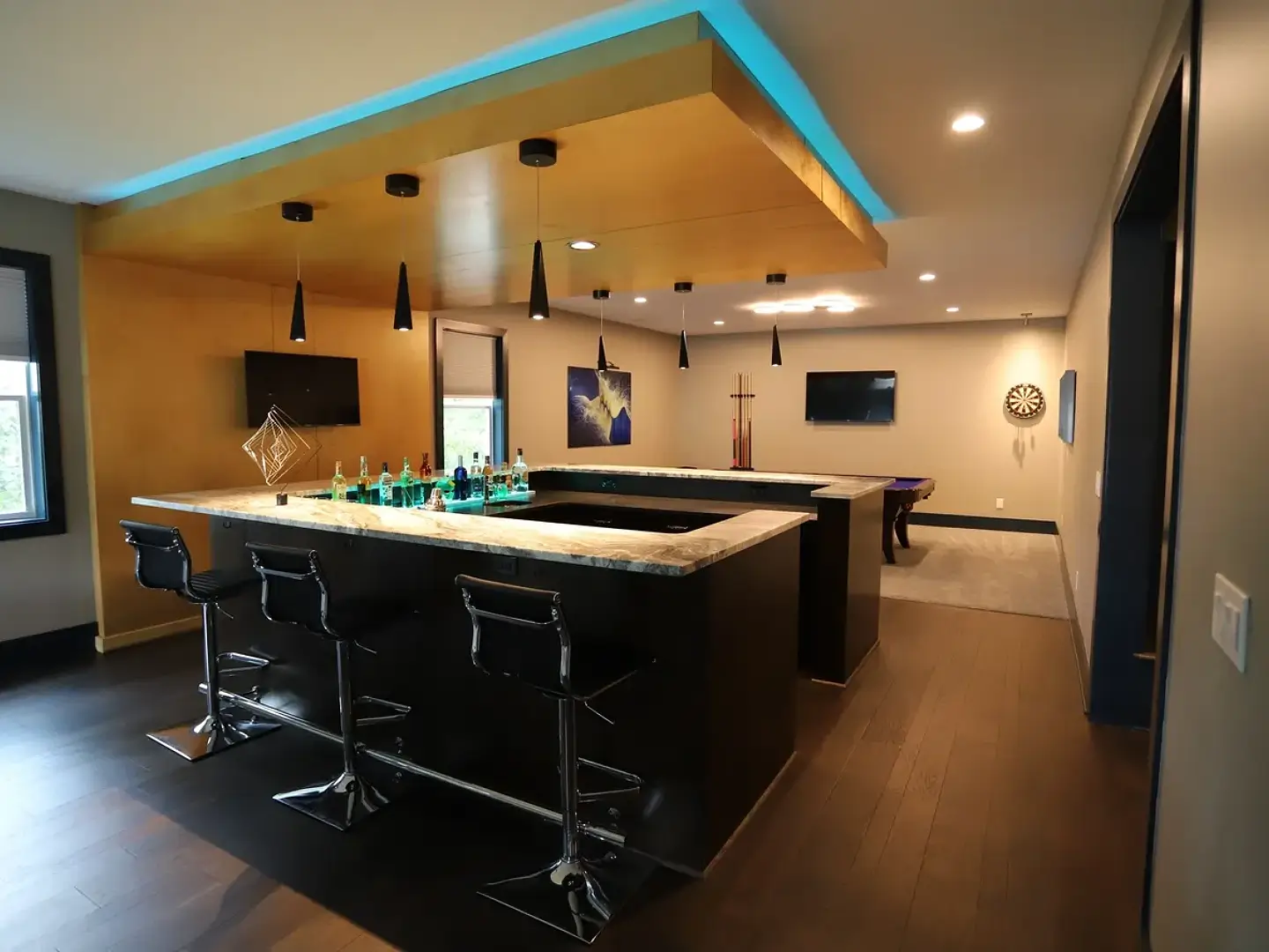 A bar with stools and lights in the ceiling.